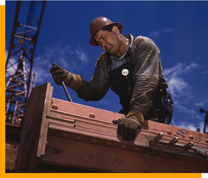 A man in hard hat working on the roof of a building.