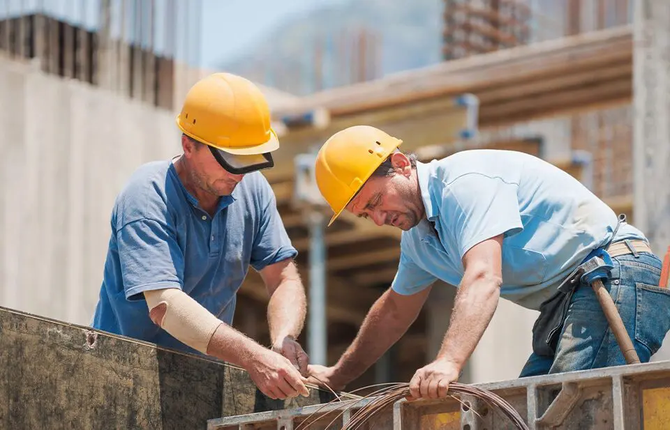 Two men in hard hats working on a building.