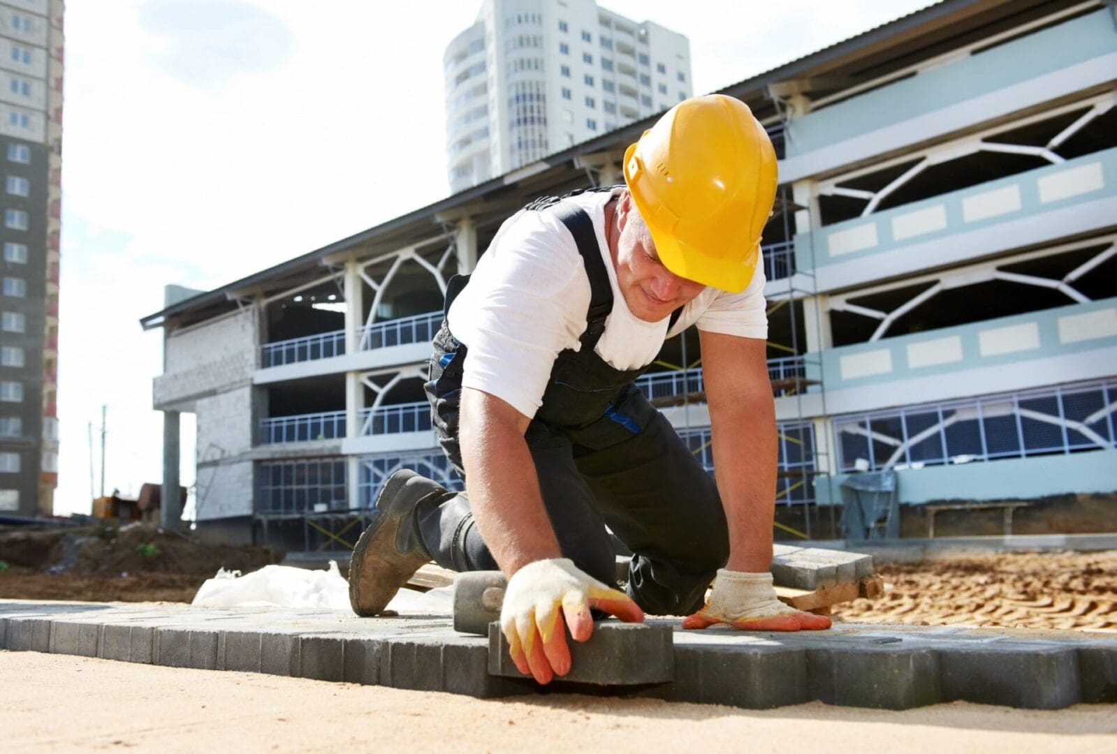 A man in yellow hard hat and gloves working on concrete.