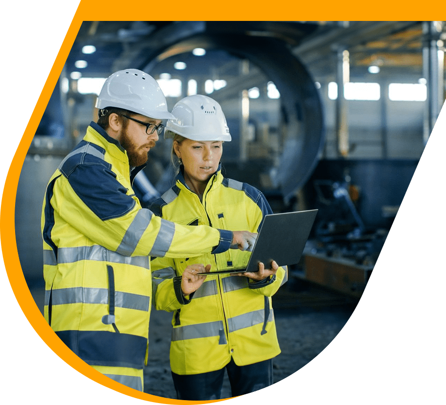 Two people in yellow jackets and hard hats looking at a laptop.