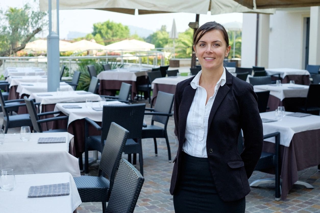 A woman standing in front of an outdoor restaurant.