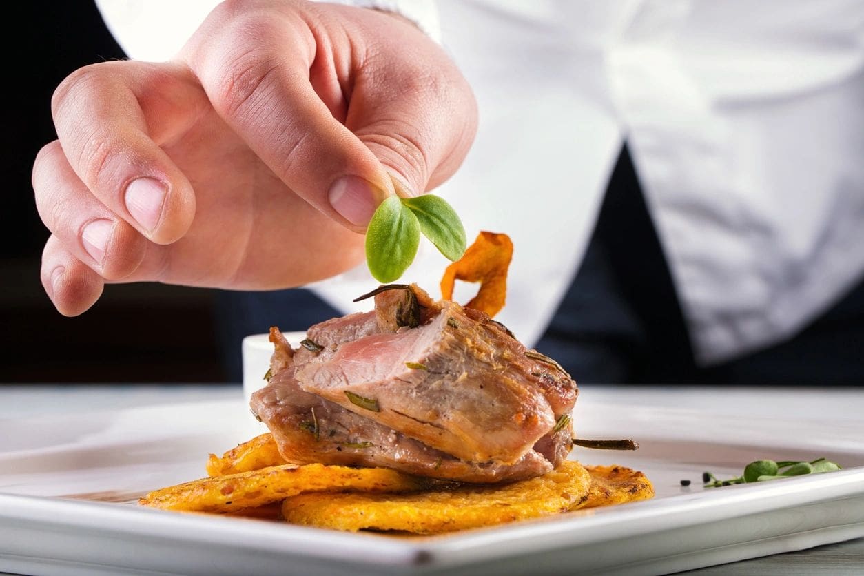 A person holding a piece of meat on top of some food.