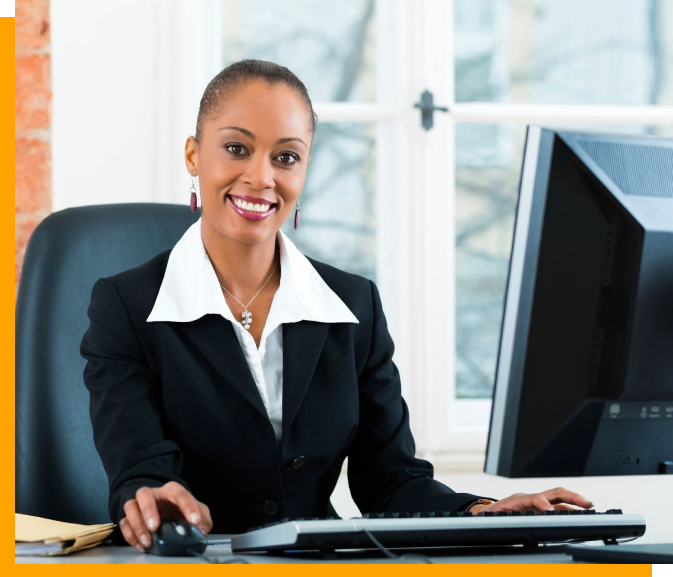 A woman sitting at her desk in front of two computers.