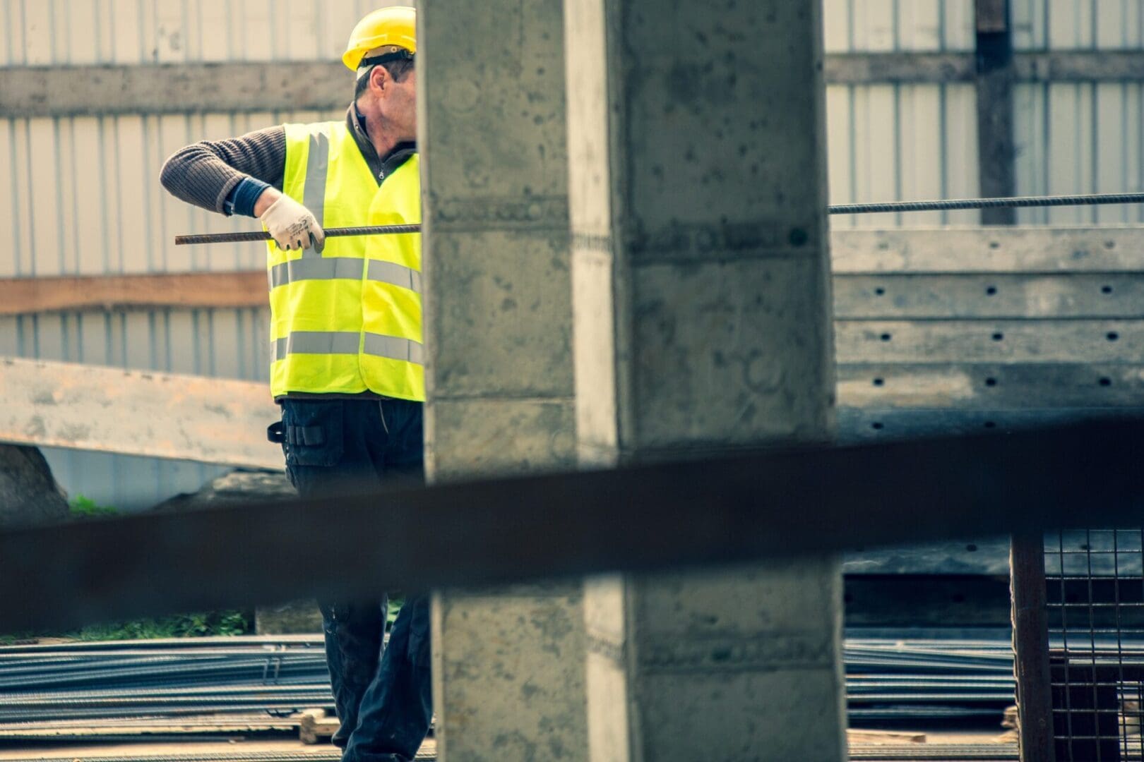 A construction worker is holding onto the pole.