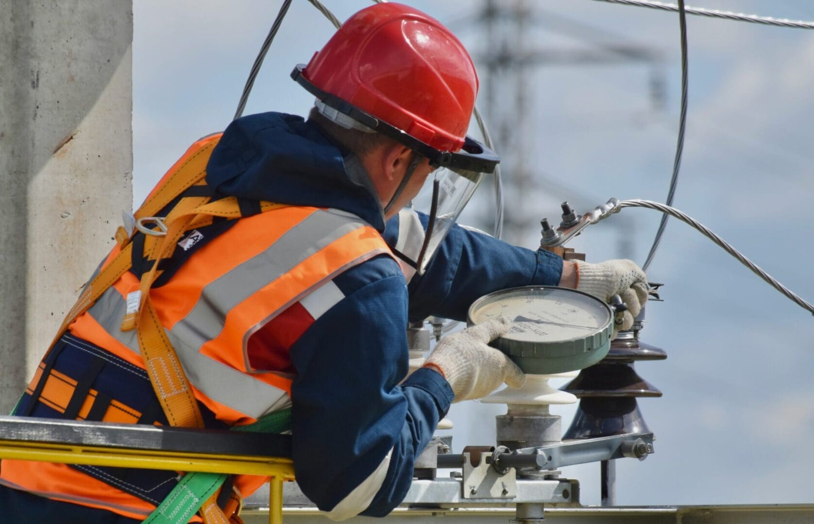 A man in an orange vest and hard hat working on a meter.