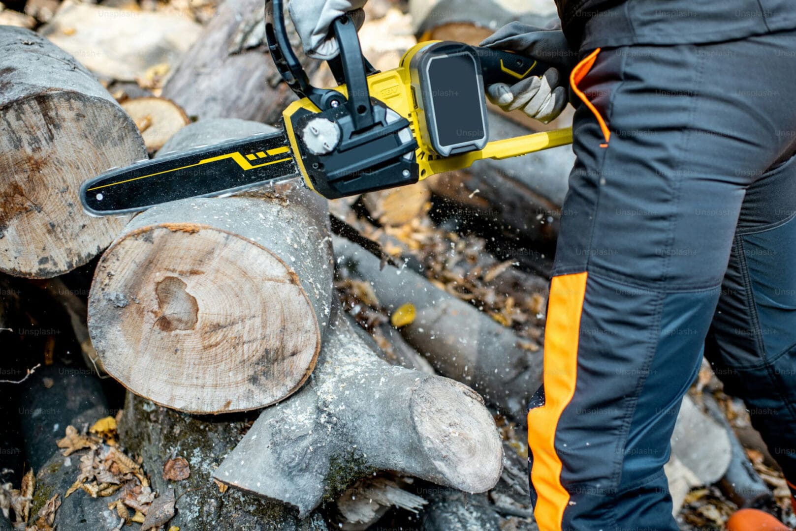 A person holding a chain saw in the woods.